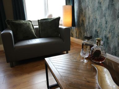A living room with a sofa, table, and decorative items at Cornerhouse Apartment 1 Llandudno