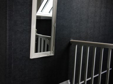 A staircase with a mirror and handrail at Cornerhouse Apartment 1 in Llandudno