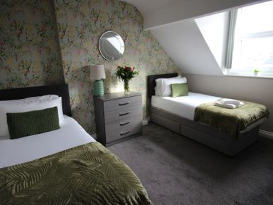 A bedroom with two beds and a nightstand at Cornerhouse Apartment 1 in Llandudno