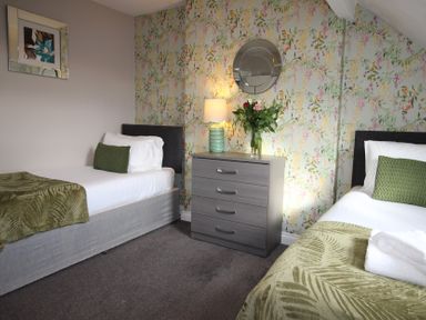 A bedroom with two beds and a dresser at Cornerhouse Apartment 1 in Llandudno