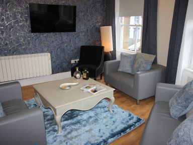 A living room with a television, sofas, and a coffee table at Cornerhouse Apartment 2 Llandudno