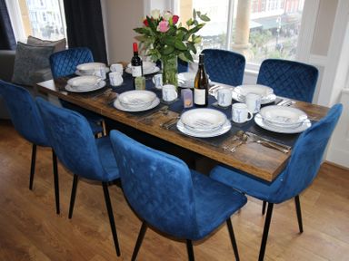 A dining room with a set table and blue chairs at Cornerhouse Apartment 2 in Llandudno