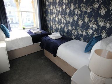 A bedroom with two single beds and a lamp at Cornerhouse Apartment 2 in Llandudno