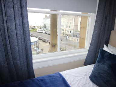A window view showing a street with cars and buildings at Cornerhouse Apartment 2 in Llandudno