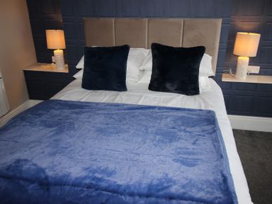 A bedroom with a bed and bedside lamps at Cornerhouse Apartment 2 in Llandudno