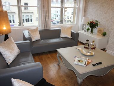 A living room with sofas, a coffee table, and a lamp at Cornerhouse Apartment 3 in Llandudno