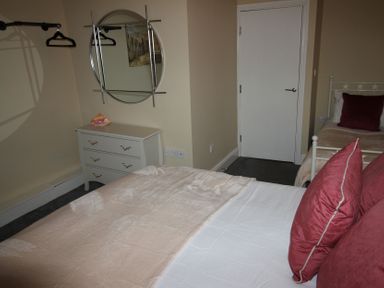 A bedroom with a bed, dressing table, and mirror at Cornerhouse Apartment 3 Llandudno