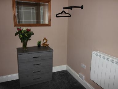 A bedroom with a drawer unit and mirror at Cornerhouse Apartment 3 Llandudno