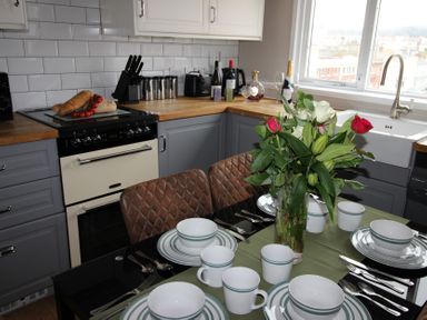 A kitchen with a dining table set and an oven at Cornerhouse Apartment 4 Llandudno
