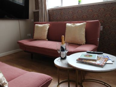 A living room with a sofa, coffee table, and television at Cornerhouse Apartment 5 in Llandudno