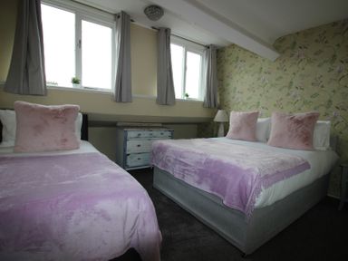 A bedroom with two beds and a dresser at Cornerhouse Apartment 5 in Llandudno