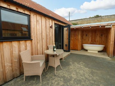 An outdoor area with a table and chairs and a bathtub at 2 West Dunkirk Neuk Hexham