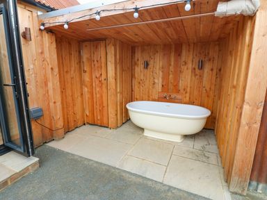 An outdoor bath area with a freestanding bathtub and wooden walls at 2 West Dunkirk Neuk Hexham