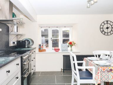 A kitchen with an oven, microwave, table and chairs at The Cheese House near Charmouth