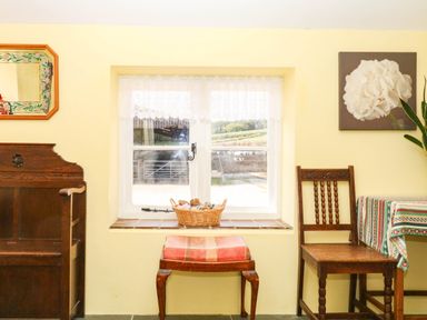 A room with a window, a wooden chair, and a basket at The Cheese House near Charmouth