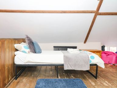 A bedroom featuring a bed with pillows and a rug at The Cheese House near Charmouth