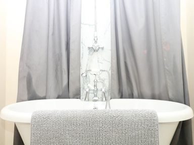 A bathtub with a faucet and gray towels at The Cheese House near Charmouth
