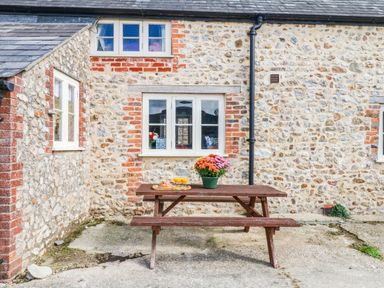 An outdoor area with a wooden table and flowers at The Cheese House near Charmouth