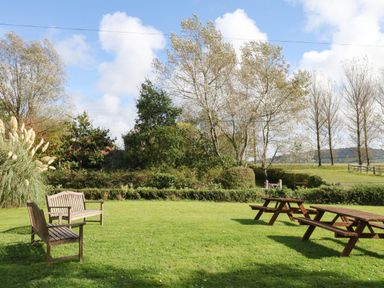 A garden with tables and benches at The Cheese House near Charmouth
