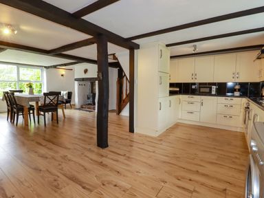 A kitchen with dining area and staircase at Honey Bee Cottage in Menheniot