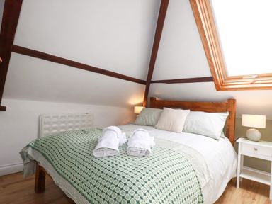 A bedroom with a bed and nightstand at Honey Bee Cottage in Menheniot