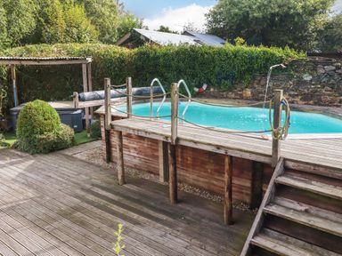 A swimming pool with wooden deck and steps at Honey Bee Cottage in Menheniot