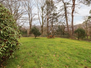 A garden with a table and chairs surrounded by trees at Irt Cottage Seascale