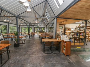 A café with tables and chairs and shelves containing various items at Irt Cottage in Seascale