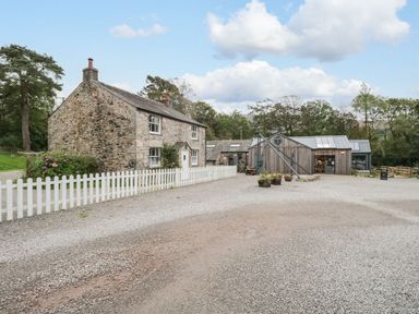 An outdoor view of a house and storage building at Irt Cottage Seascale
