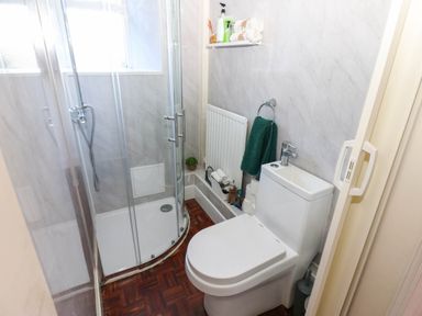 A bathroom with a shower, toilet, and radiator at Prudhoe Cottage in Prudhoe
