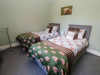 A bedroom with two beds and a clothes rack at Prudhoe Cottage in Prudhoe