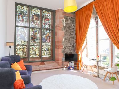 A living room with a stained glass window and sofa at Flat 16 in Criccieth