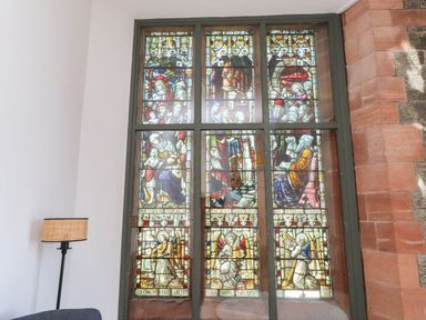 A stained glass window with various figures at Flat 16 in Criccieth