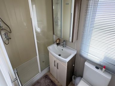 A bathroom with shower, sink, and toilet at Lyons Robin Hood in Rhyl