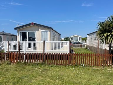 A static caravan with a deck and fenced area at Unity Beach in Burnham-on-Sea