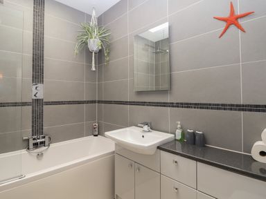 A bathroom with bathtub, sink, and mirror at The Old Dairy near Liskeard