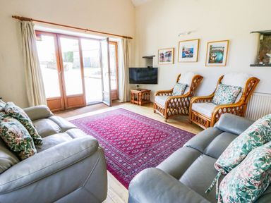 A living room with a sofa and armchairs at May Cottage in St Davids