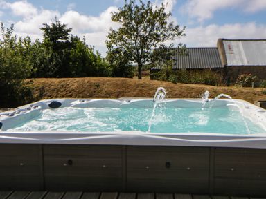 A hot tub with water jets in an outdoor garden at May Cottage St Davids