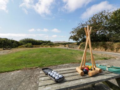 A croquet setup with mallets and balls on a table in an outdoor area at May Cottage St Davids
