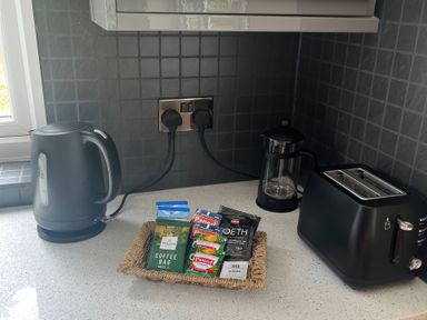 A kitchen counter with kettle, toaster, coffee, and tea bags at Saddleback Bungalow in Llandrindod Wells