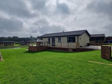 A lodge with a patio and grass area at Pet Friendly 2Bed Luxury Lodge in Routh HotTub Heron Lakes Luxury Lodge Park near Beverley
