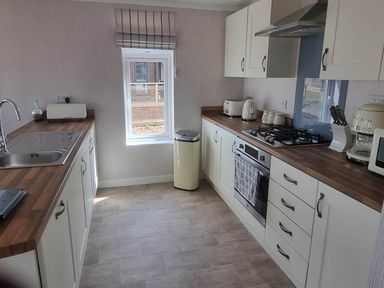 A kitchen with a sink, gas stove, and window at Pet Friendly 2Bed Luxury Lodge in Routh HotTub near Heron Lakes Luxury Lodge Park near Beverley