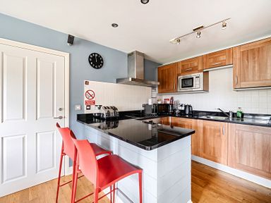 A kitchen with stools and appliances at 2bed sleeps4 pool freeparking Trenythonestate near Par