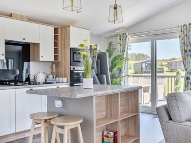 A kitchen with stools and appliances at Atlantic Breeze Luxury Lodge sleep 6 Mullacott near Ilfracombe