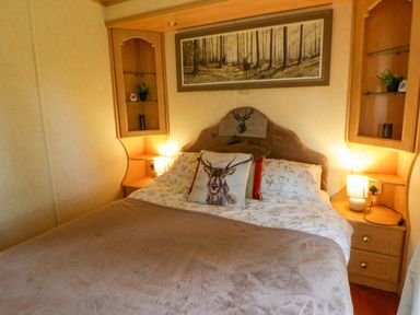 A bedroom with a bed and walls shelves at Leven in Lampeter