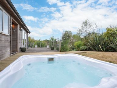 An outdoor area with a hot tub near a wooden deck at 5 Tree Tops in Dobwalls