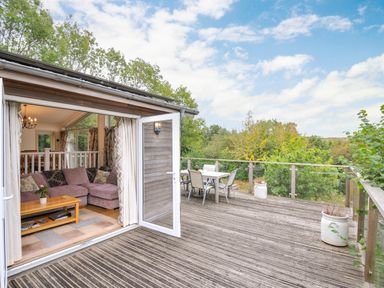 A deck area with a couch and outdoor dining table at 5 Tree Tops in Dobwalls