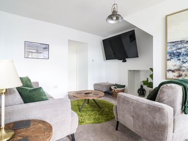 A living room with a sofa, coffee table, and television at 1 Glanaber Terrace