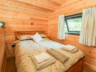 A bedroom with a bed and window at Sycamore Lodge in Brecon