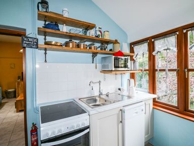 A kitchen with a stove, sink, microwave and shelves at The Old Forge in Kingsbridge